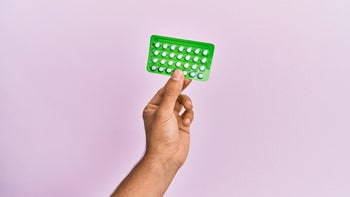 Health: birth control: tan hand holding birth control pill pack-1288605120