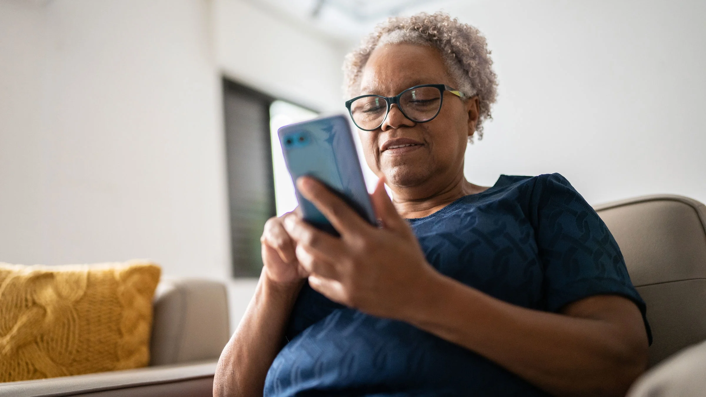 A senior woman uses a mobile phone at home.