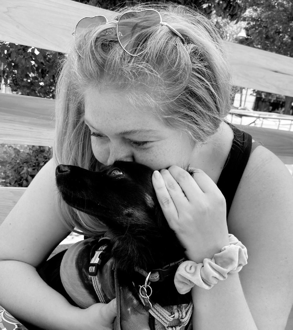 B&W photo of Hayley Chamblin cuddling with a dog.