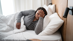 A woman clutches her forehead in discomfort as she lies in bed with a headache.
FG Trade/E+ via Getty Images 