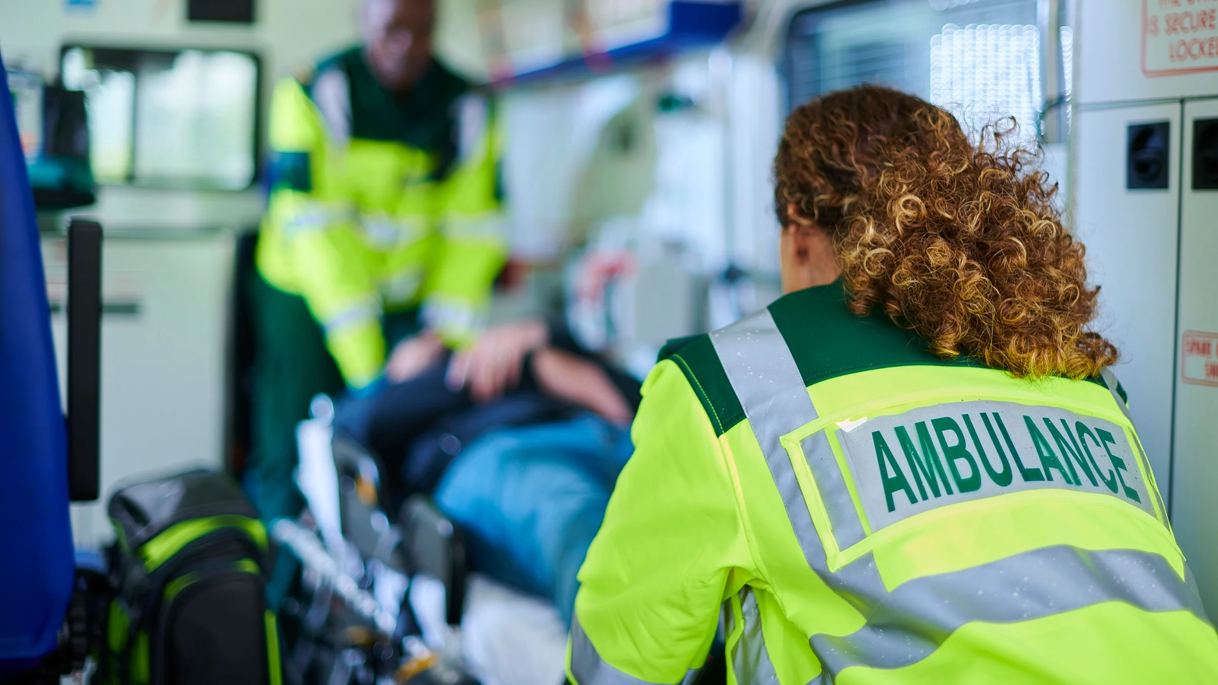 An EMT ushering a patient on a stretcher into an ambulance.