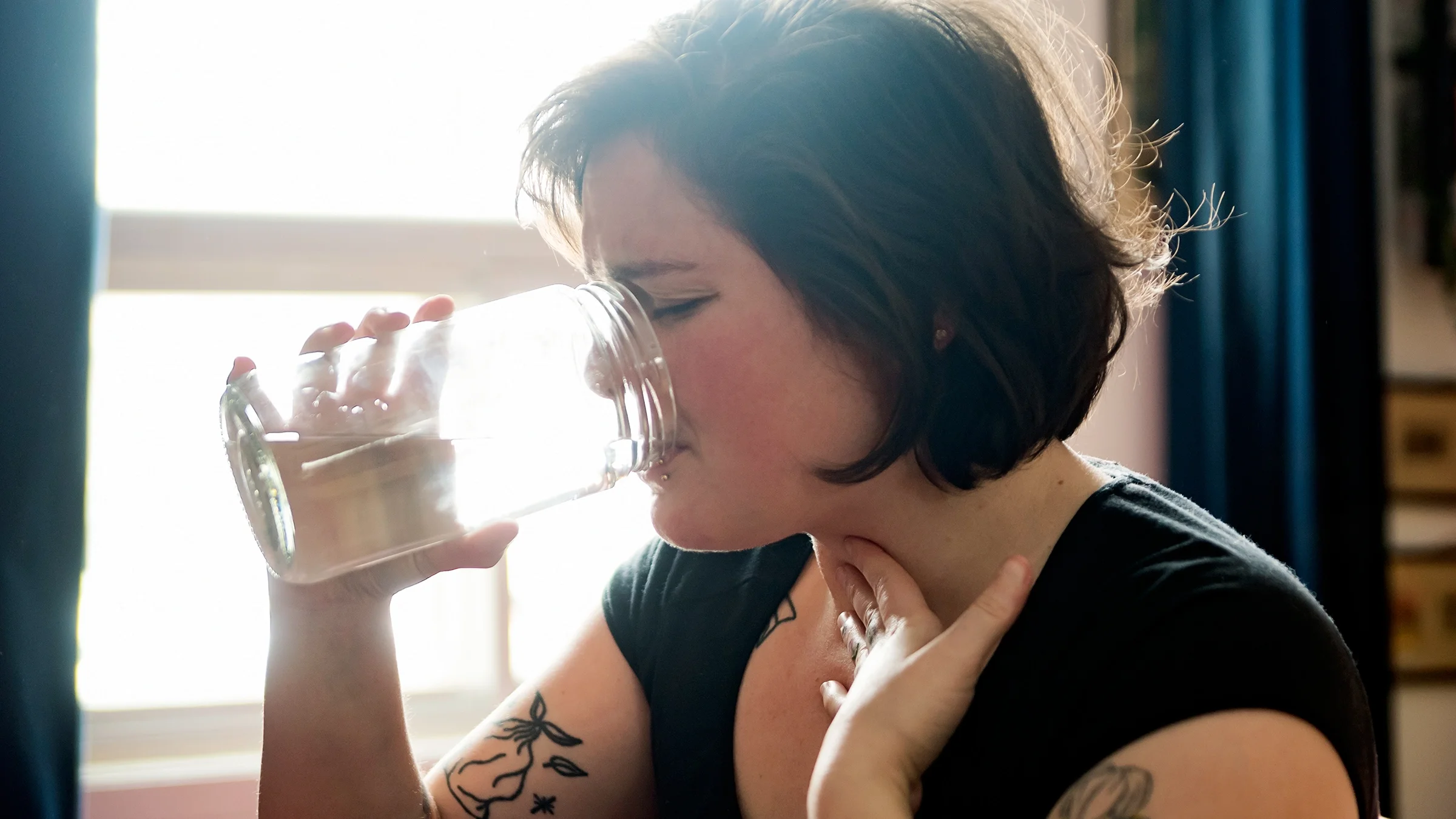 Woman with sore throat drinking water.