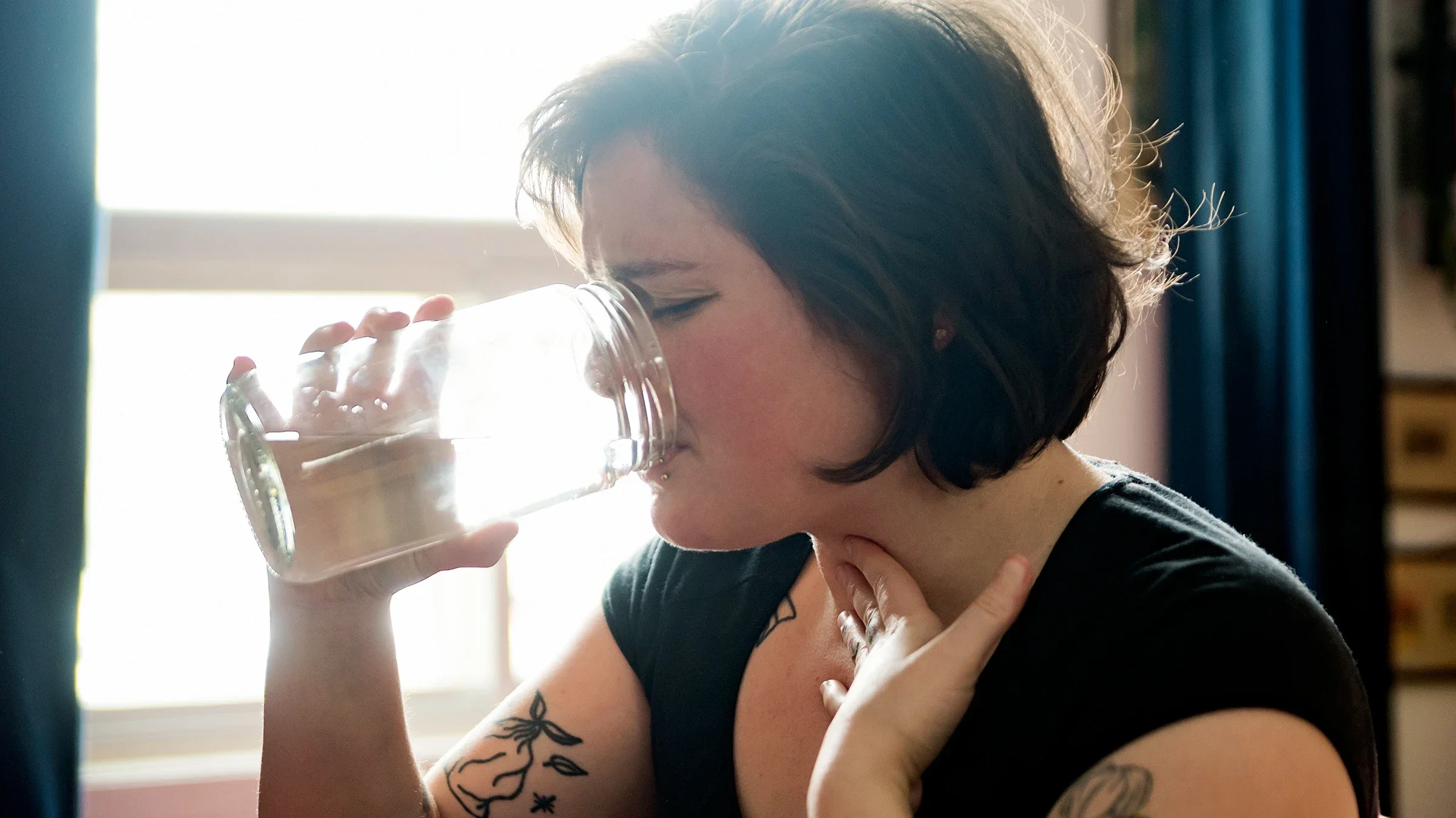 Woman with sore throat drinking water.
martinedoucet/E+ via Getty Images 