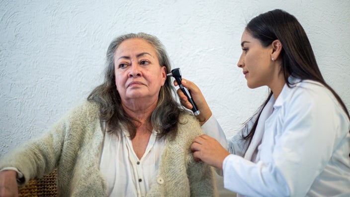 A healthcare provider is examining an older adult’s ear.