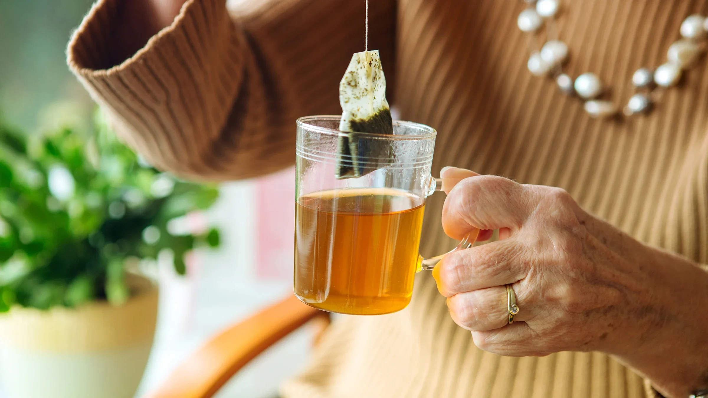 A woman's hand holds a glass of tea with a teabag.
wernerimages/iStock via Getty Images Plus