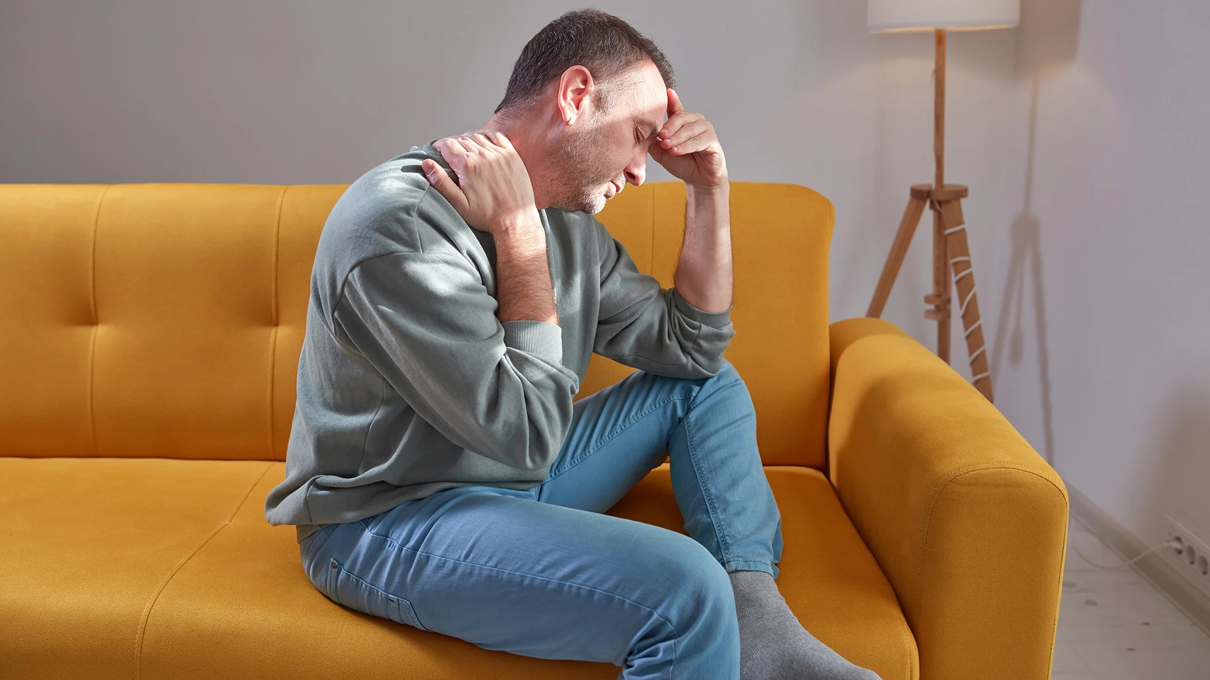A man with shoulder and neck pain at home.
