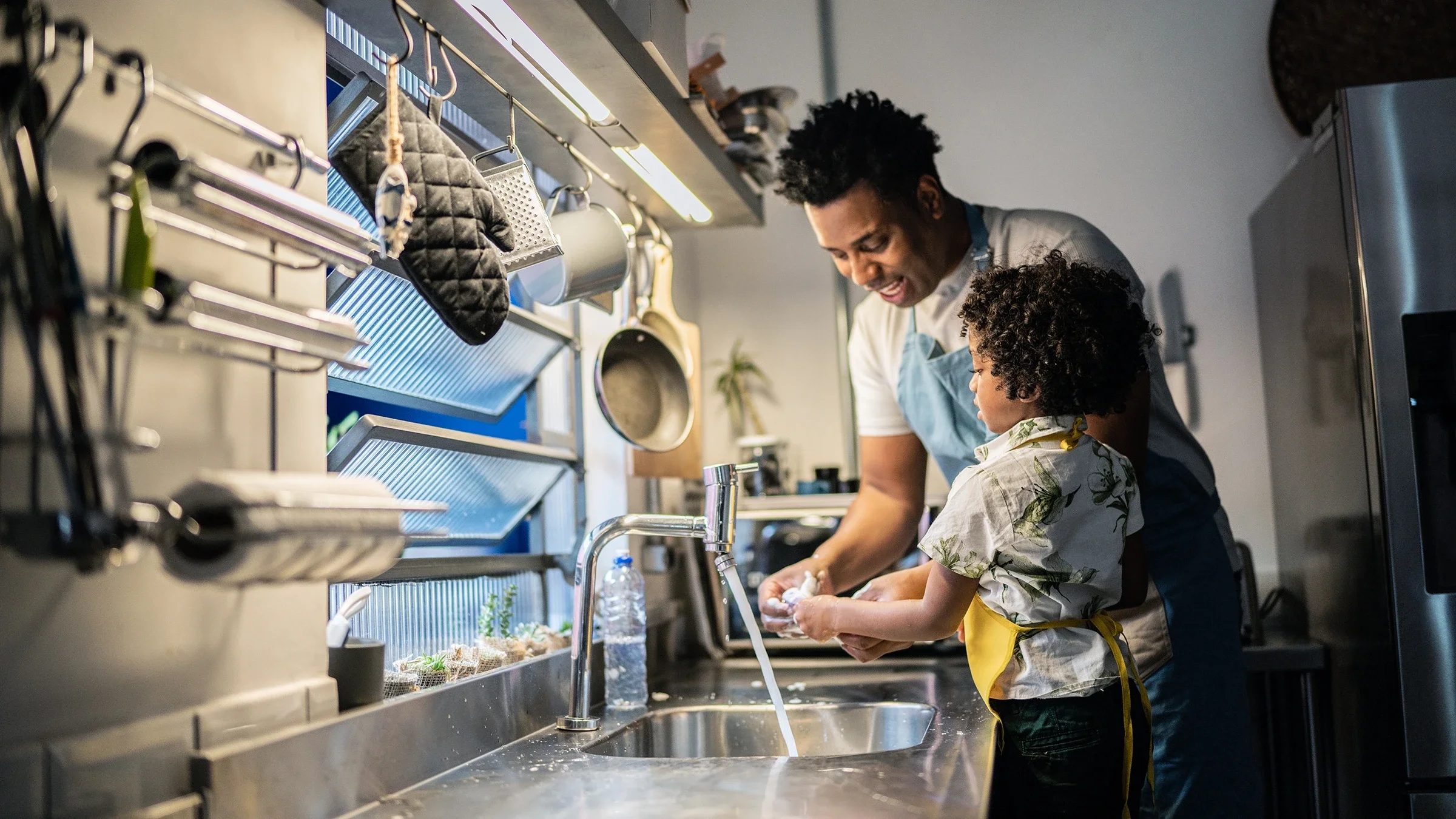 A father and son are washing dishes at home.