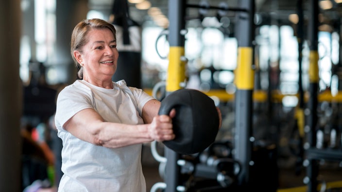 A woman exercises with a medicine ball at the gym.