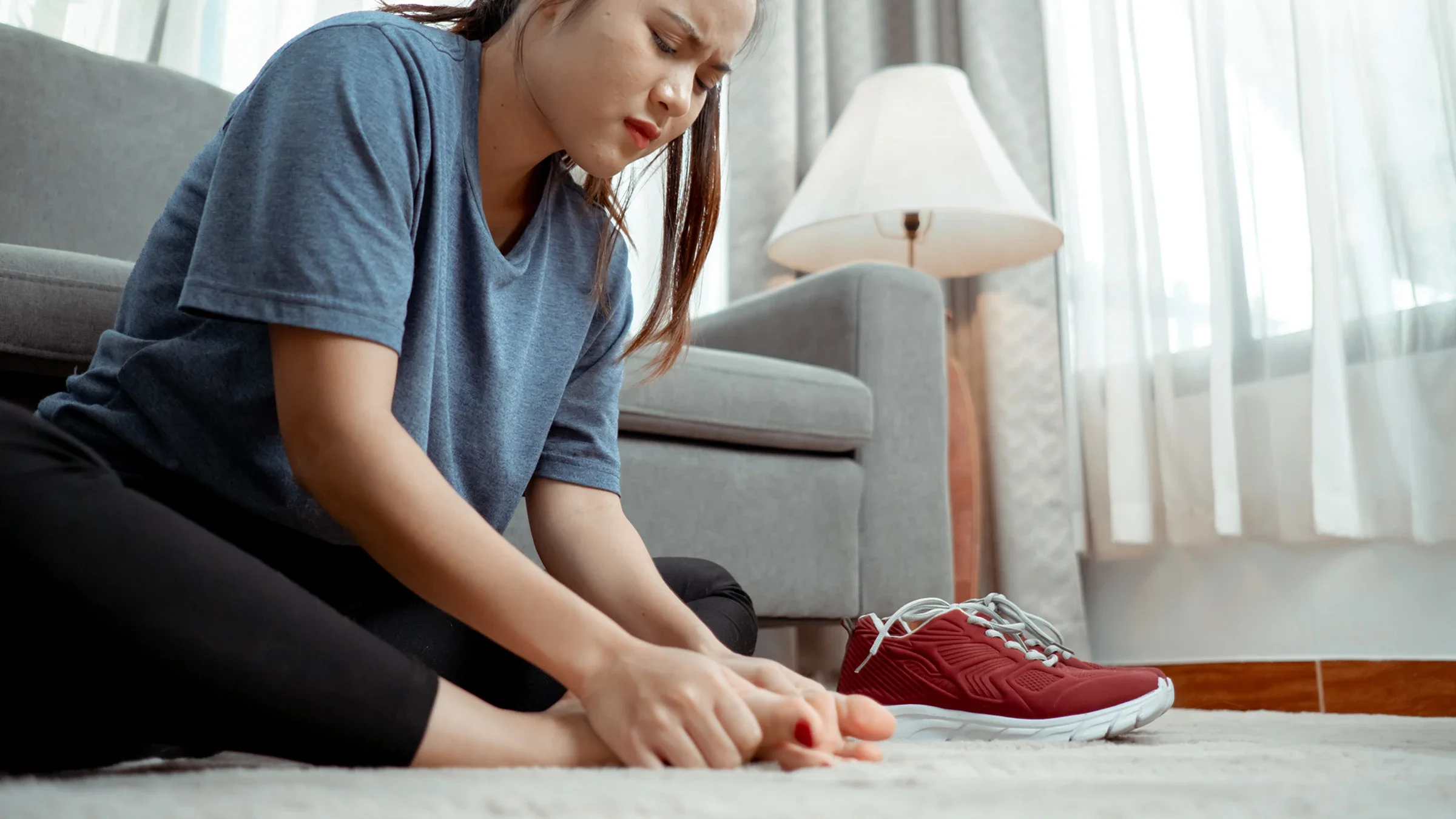 Woman sitting with foot pain at home in the living room.
champpixs/iStock via Getty Images Plus