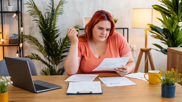 A woman reviews her medical bills at home.
