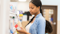 A woman reads the back of a medication box at a pharmacy. 
SDI Productions/E+ via Getty Images Plus
