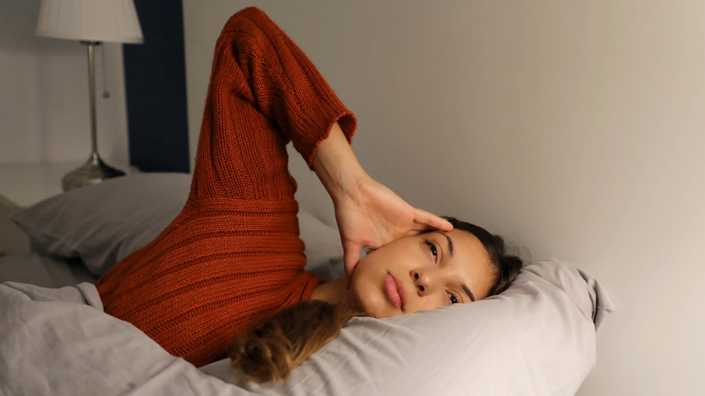 A young woman with a headache in bed.