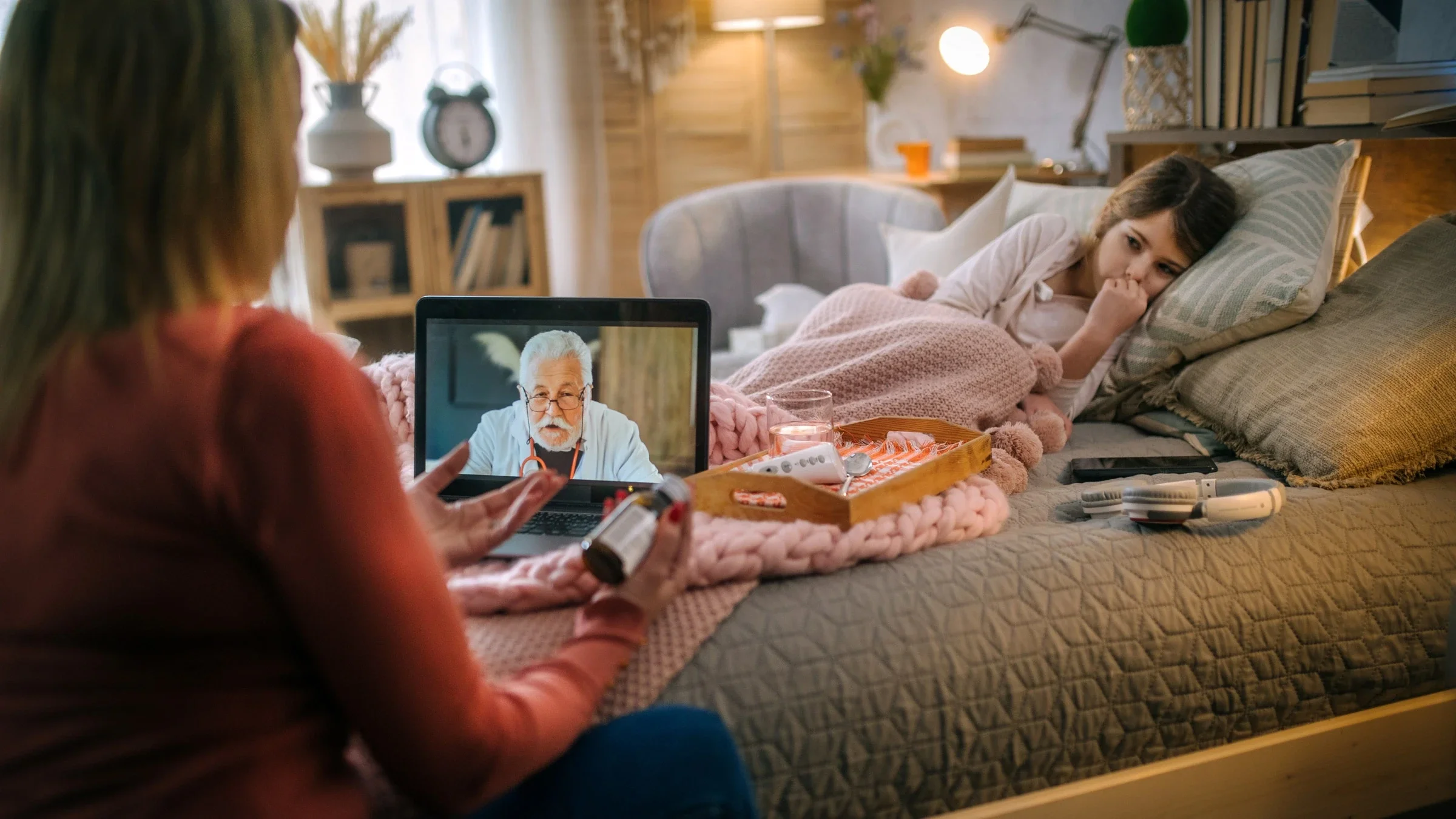 A parent in a telehealth call, with their sick child in the background.