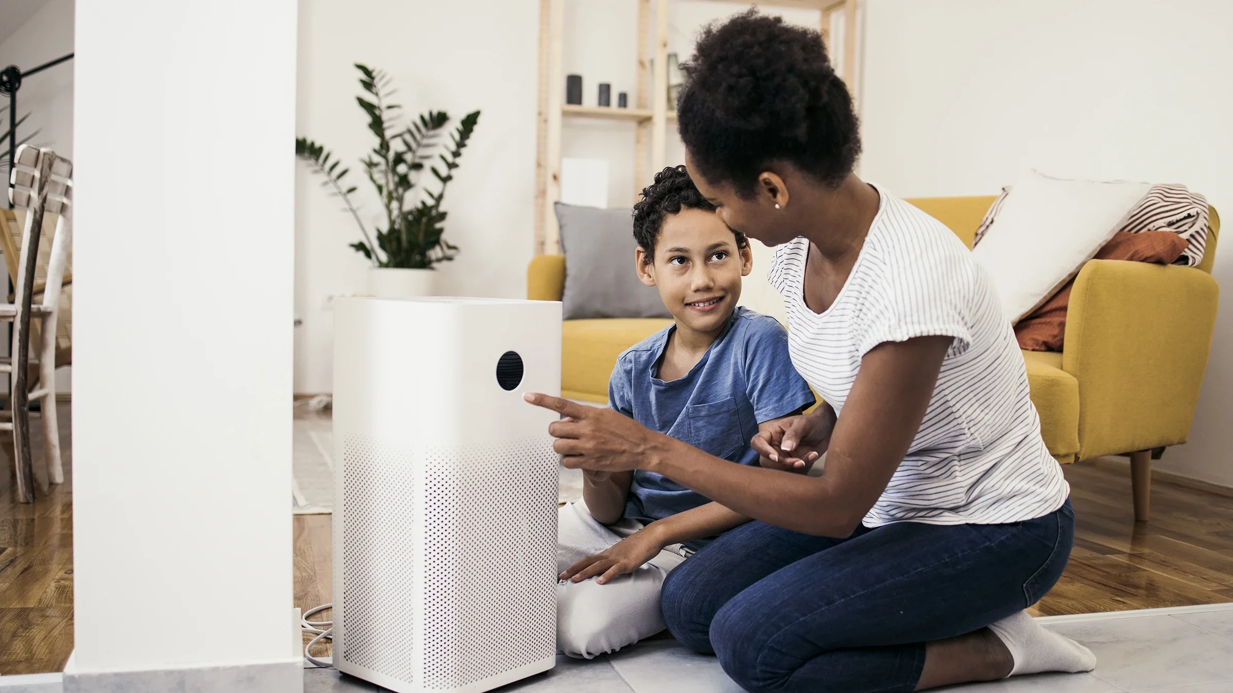 A mother and son set up an air purifier at their home. Air purifiers can help remove allergens from the air.