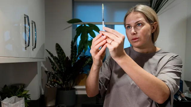 Medication basics: woman examining syringe at home 2101441528