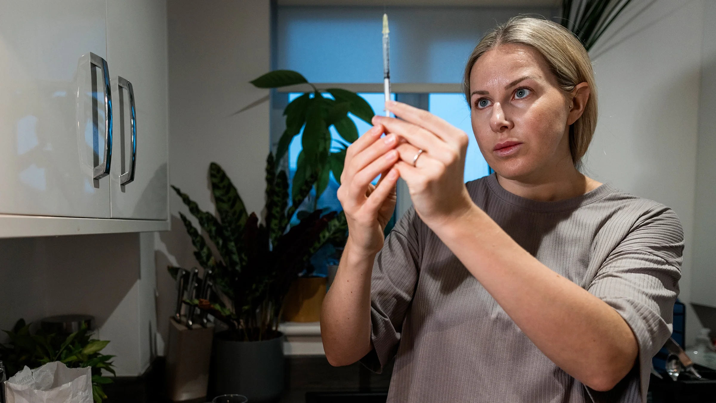 A woman examines a syringe before administering an injection.