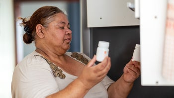 menopause: woman reading medicine bottles 1426369188