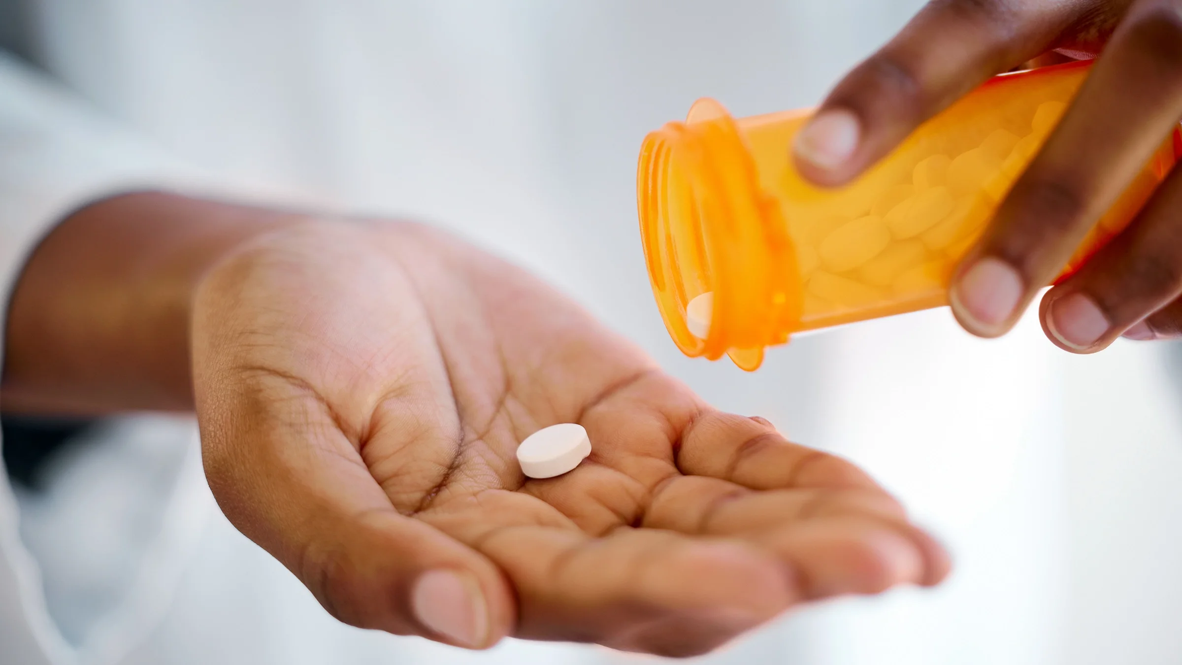 A close-up of someone pouring medication into their palm.