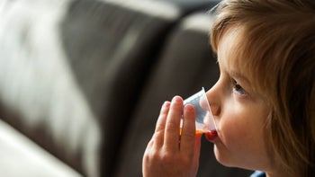 Childrens health: child drinking medicine out of dose cup 1218758024