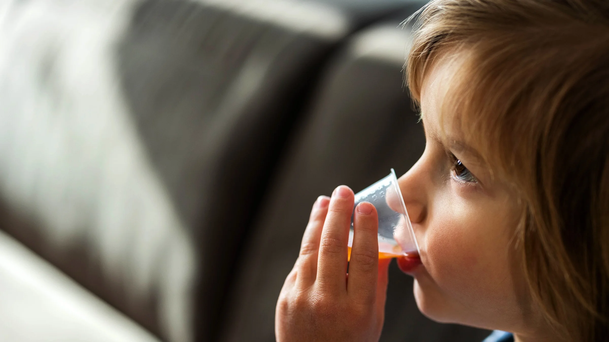 A child drinks medicine from a dose cup.