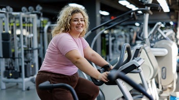 Health-insurance: woman smiling on exercise bike 2157402085
