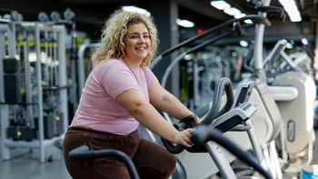 Health-insurance: woman smiling on exercise bike 2157402085