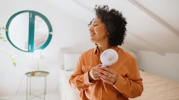 veozah: woman cooling off with portable fan 2250699870