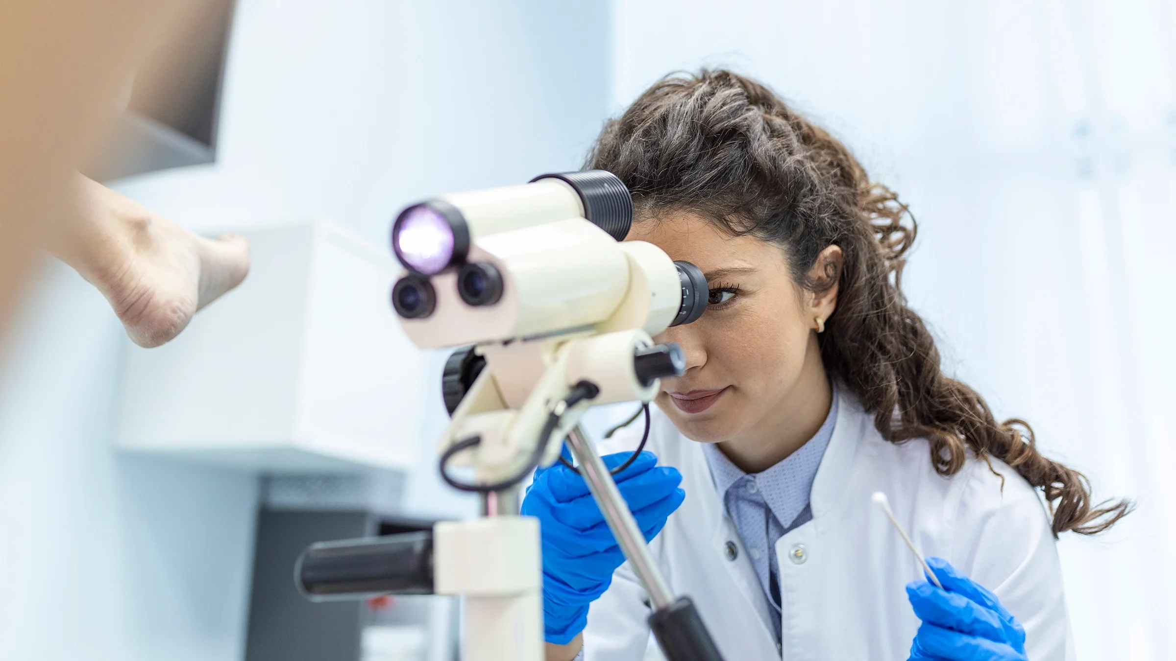 Gynecologist exam with a scope between a woman's legs in stirrups.