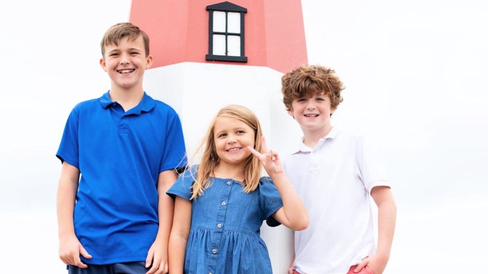 Mary Beth Cunningham’s children — Shane, Molly, and Colin — are pictured in a vacation snapshot in front of a lighthouse.
