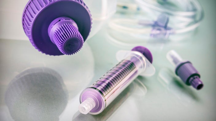 Close-up of a purple syringe and bottle nutritional device called a PEG tube.