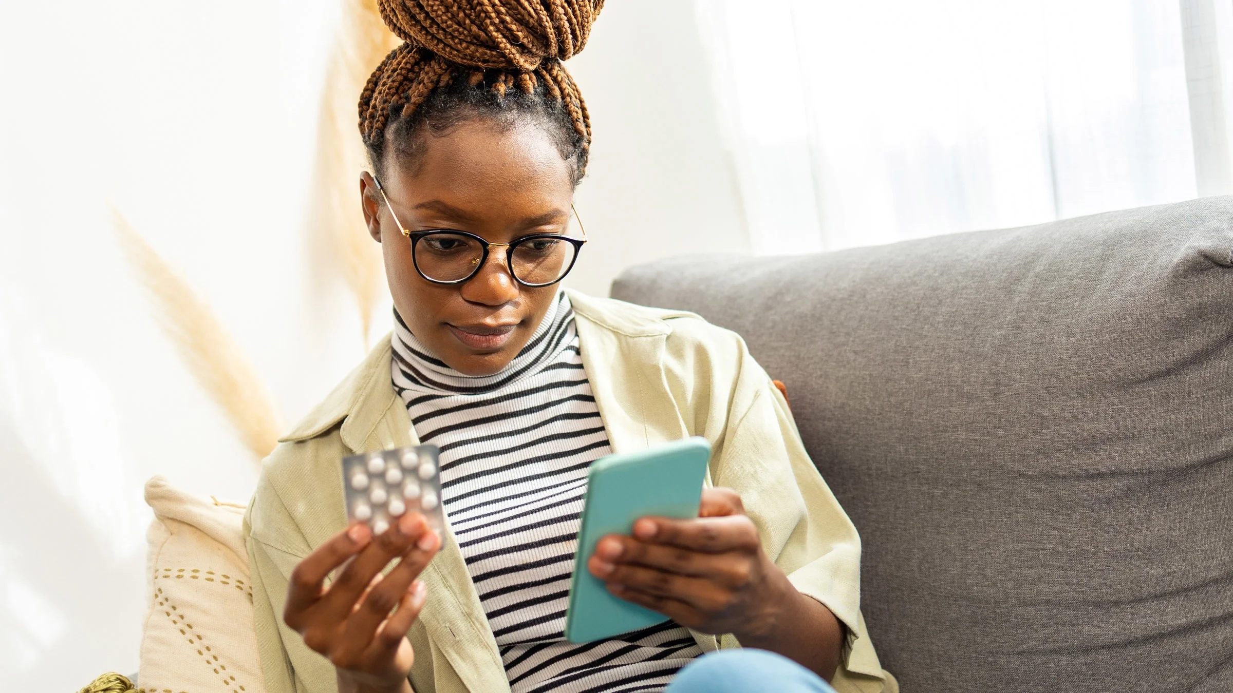 A person holding a blister pack and using their phone.