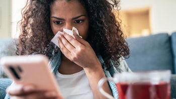tamiflu: blowing nose looking at phone 1218047526