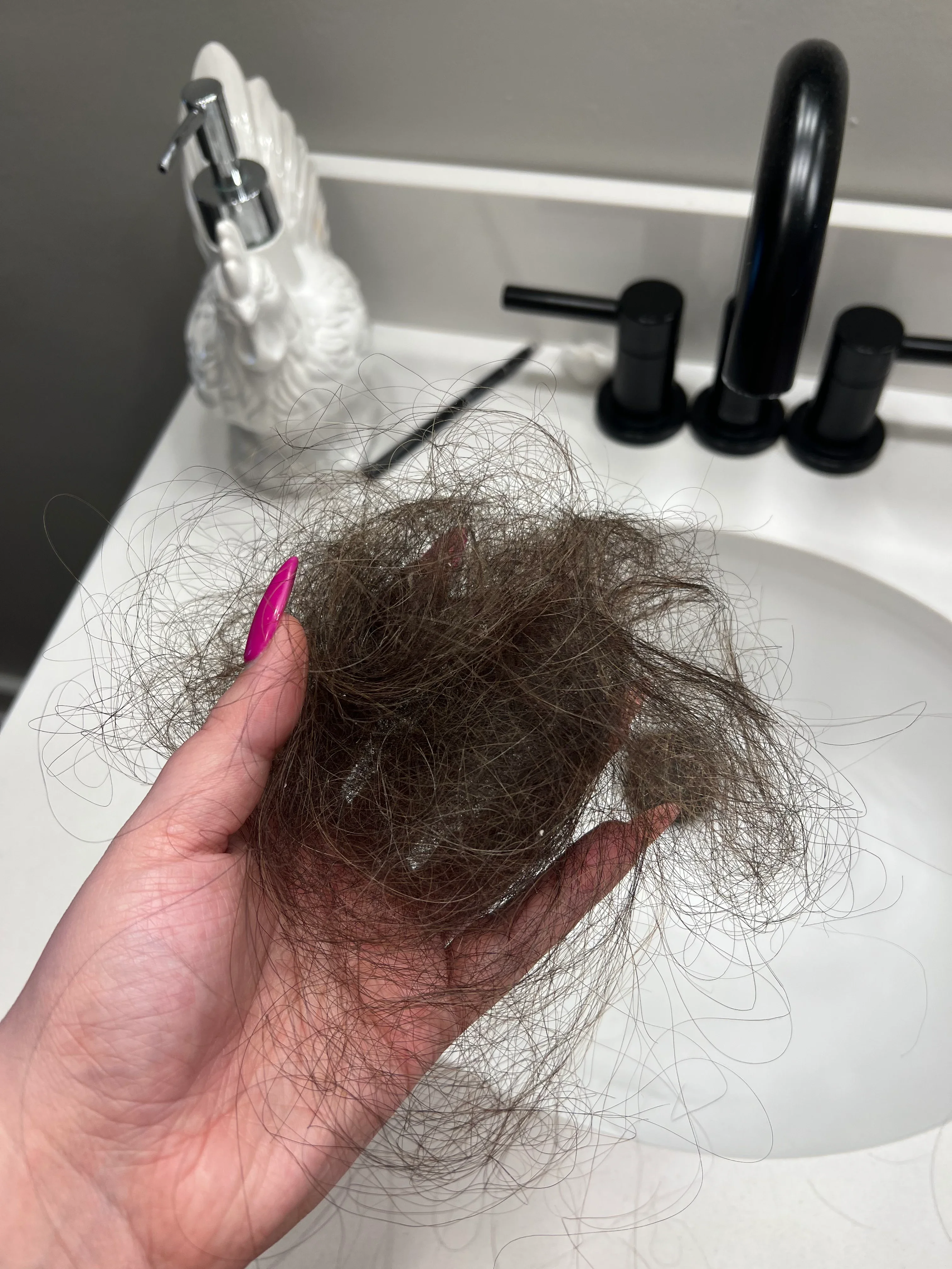 Photo of Michaela Pearson holding a clump of hair over her bathroom sink.