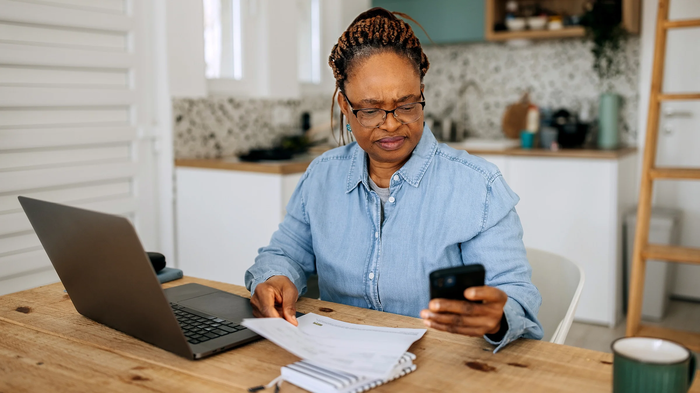 A woman is calculating her expenses at home.