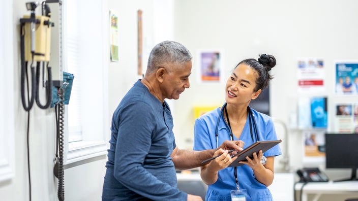 An older man interacts with a clinician in an exam room.