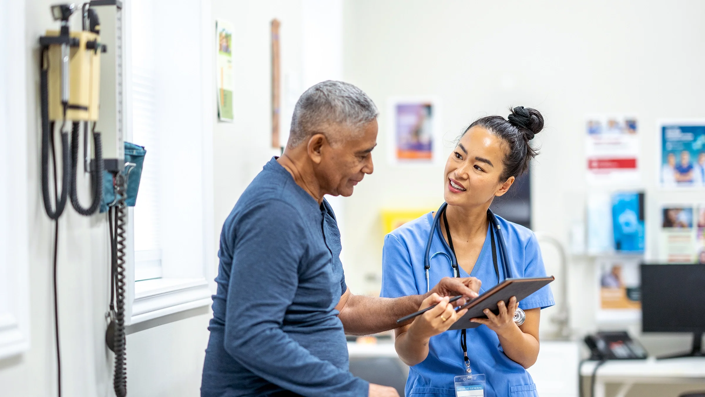 An older man interacts with a clinician in an exam room.