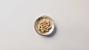 Diet nutrition: adaptogens: ashwagandha pills in bowl white background-1347280312