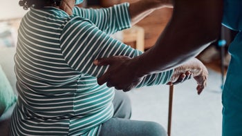 Health: ALS: cropped nurse helping woman up as she uses her cane-1316049538
