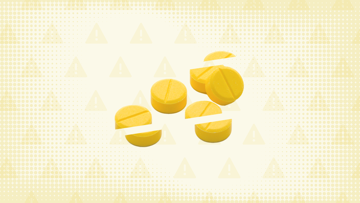 ellow background with textures and warning sign pattern. In the center is a pile of round yellow pills cut into thirds.