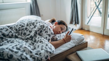 Long COVID: tired in bed looking at phone 1203519740