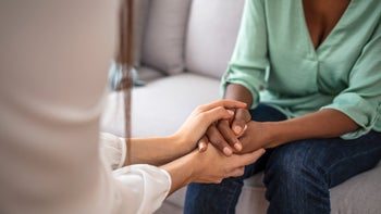 Health: Substance use: two women holding hands in comfort-1334410357