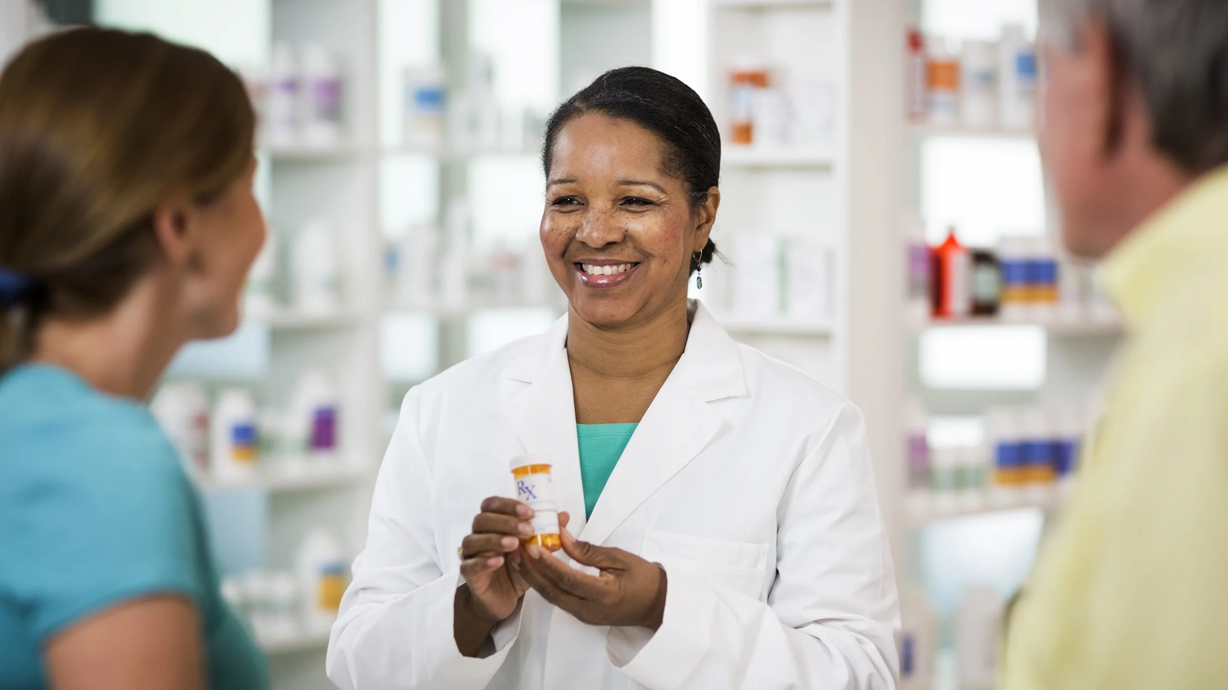 A man and woman pick up a prescription at a pharmacy.