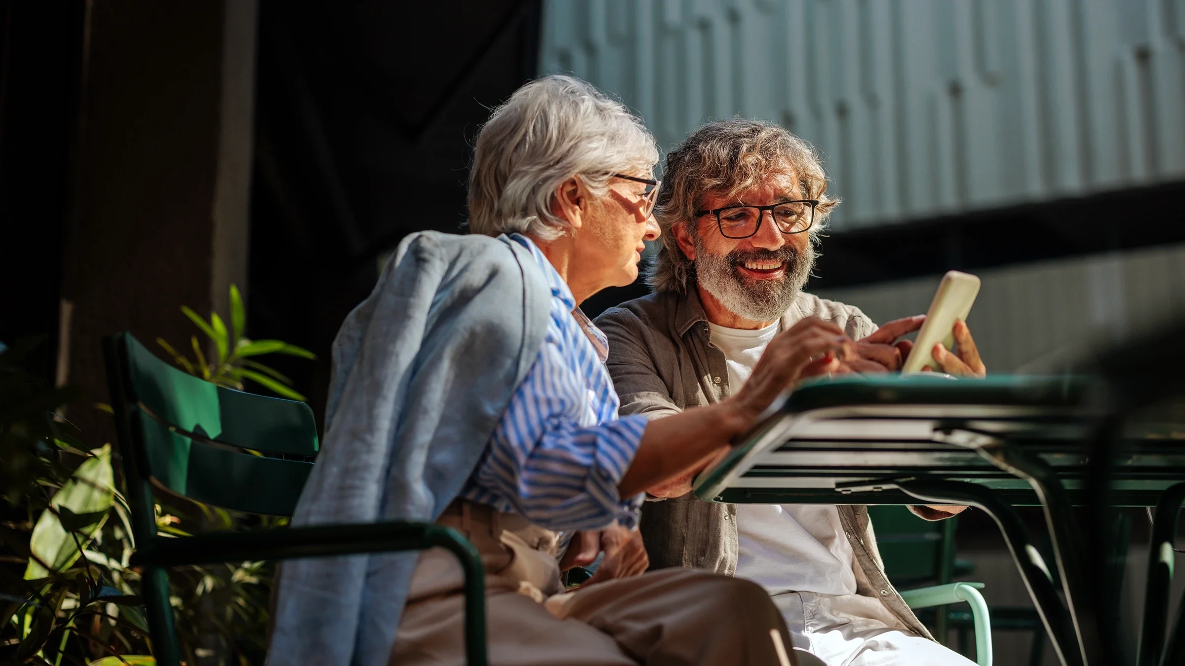 A man and woman look at a smartphone.