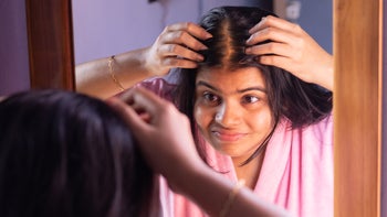 Birth control: woman checks hair loss problem in front of mirror 1440665027