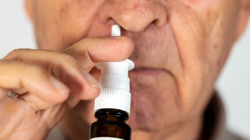 flonase: closeup senior man using nasal spray 1127349261