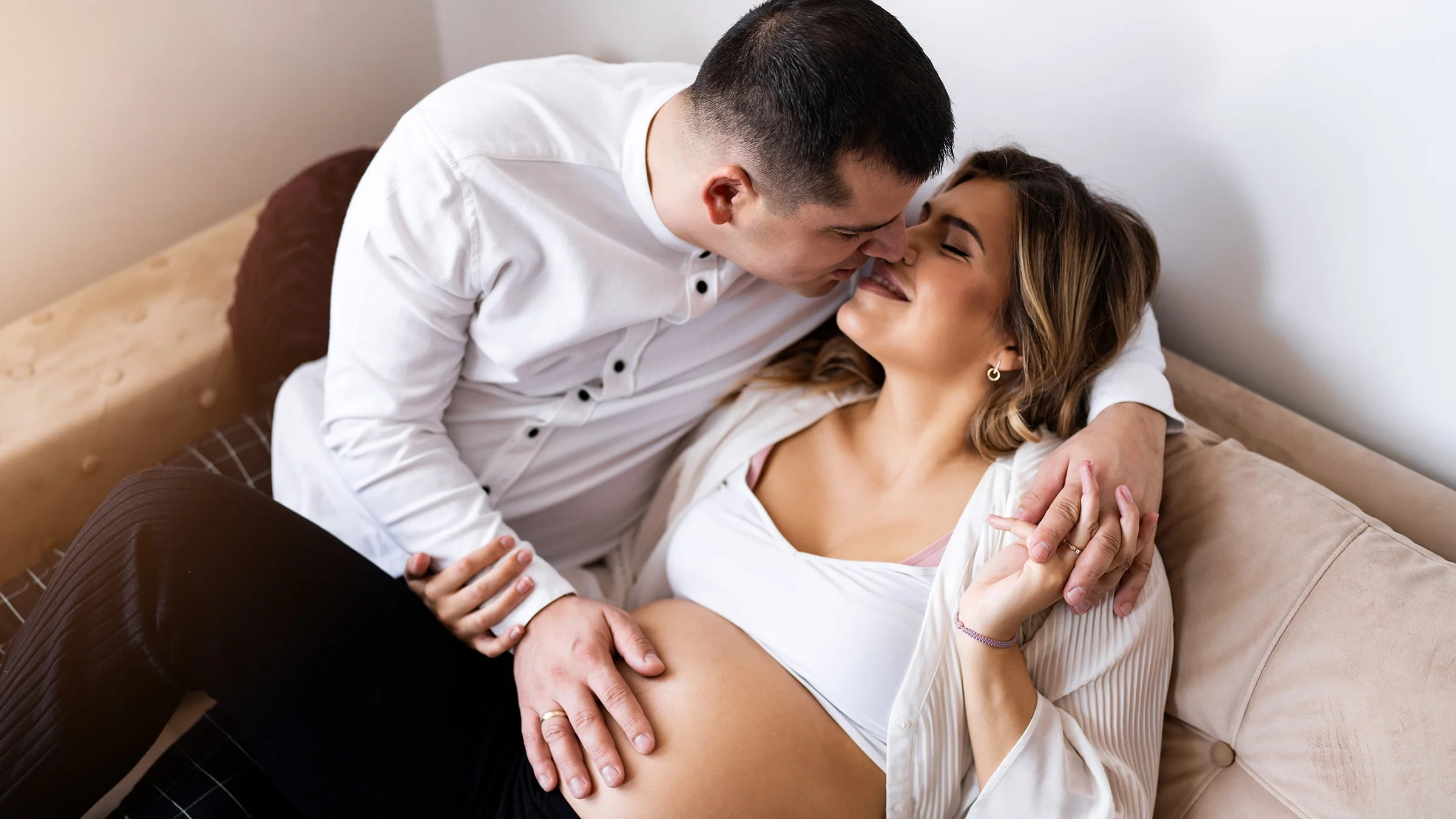 Pregnant woman and man kissing on the sofa.