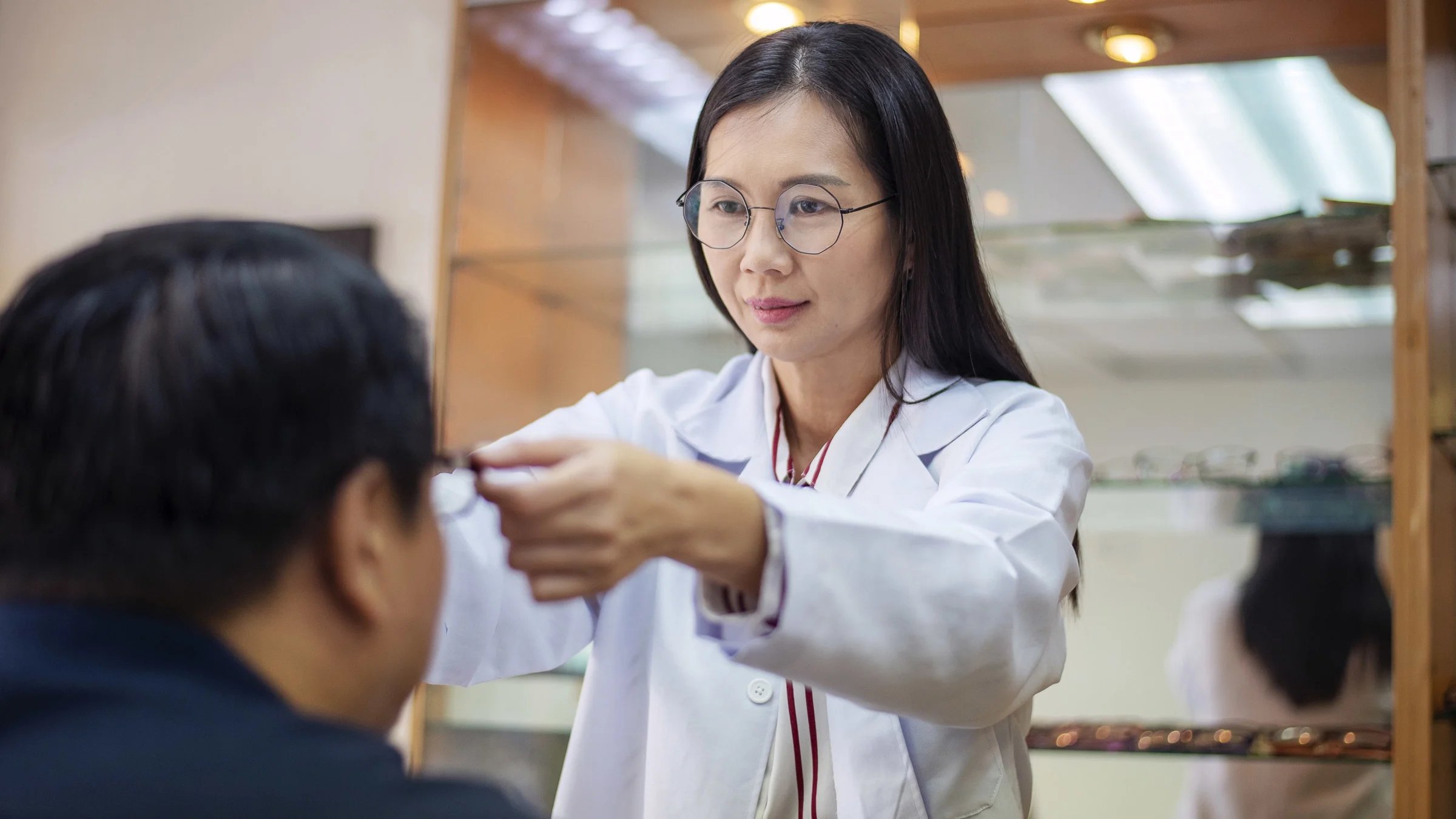 A optometrist helping a patient try on glasses.