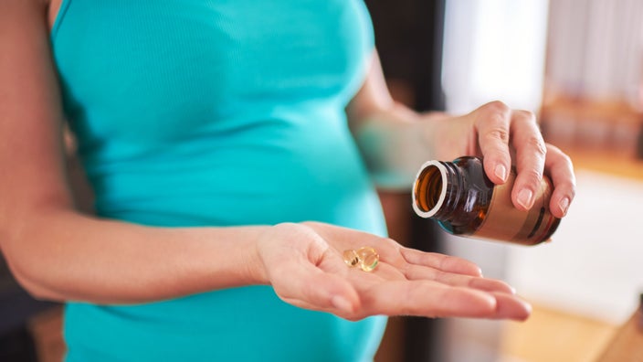 Close-up pregnant woman with pill capsules in hand.