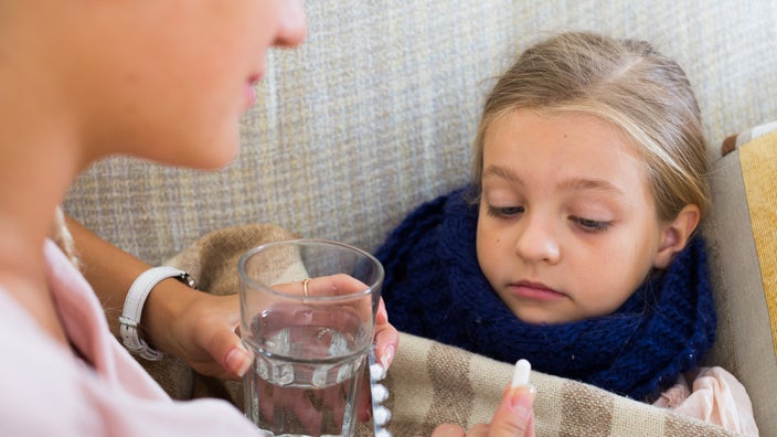 A parent giving a pill to a sick child.