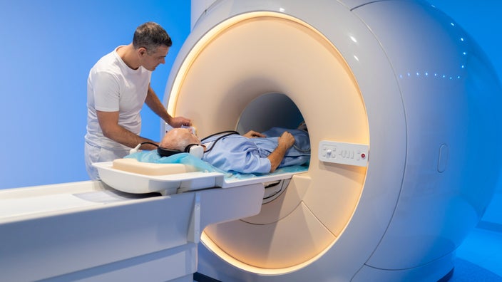 A doctor helping a patient enter an MRI scanner.